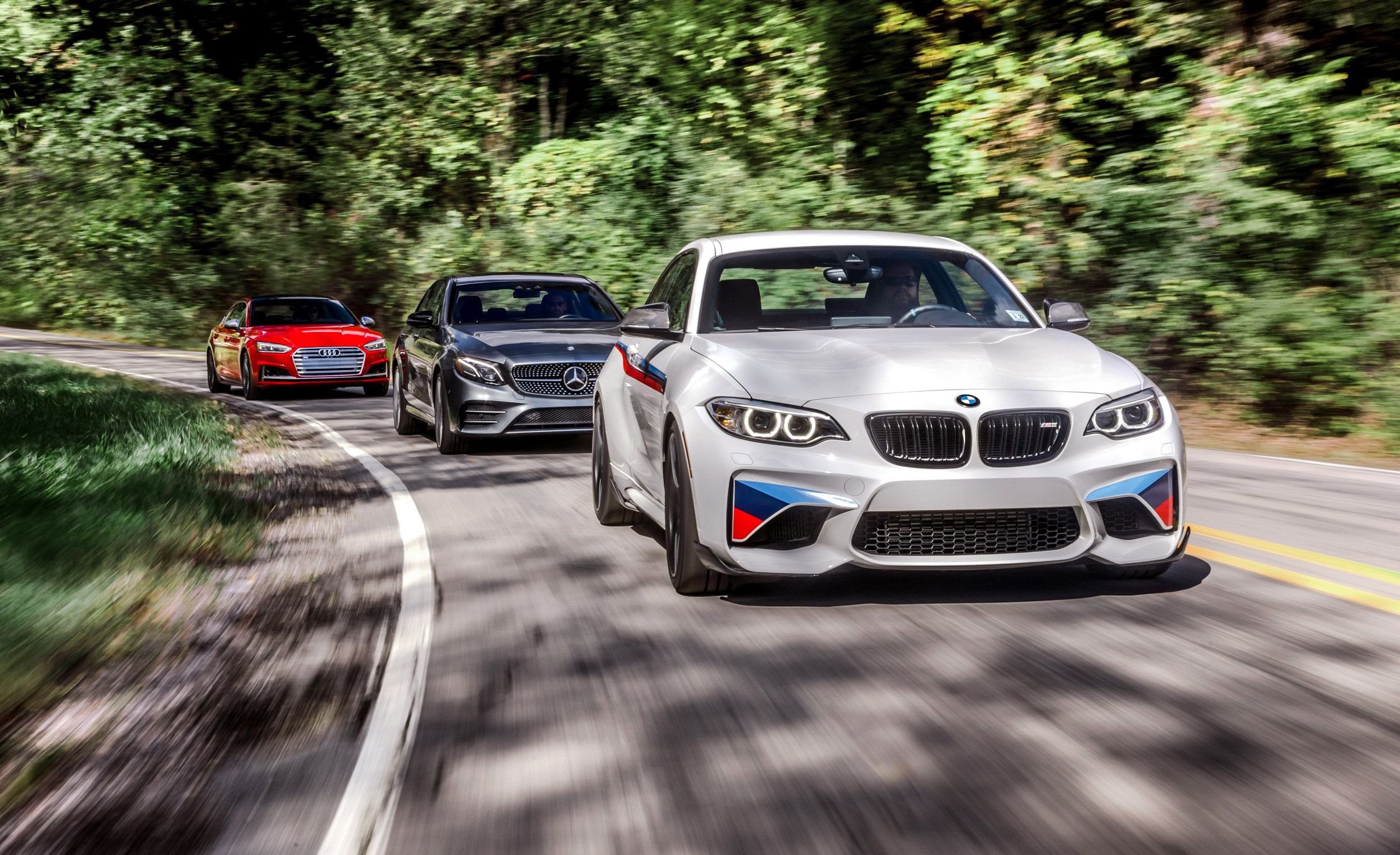 German luxury cars - BMW, Mercedes, and Audi driving on a winding road
